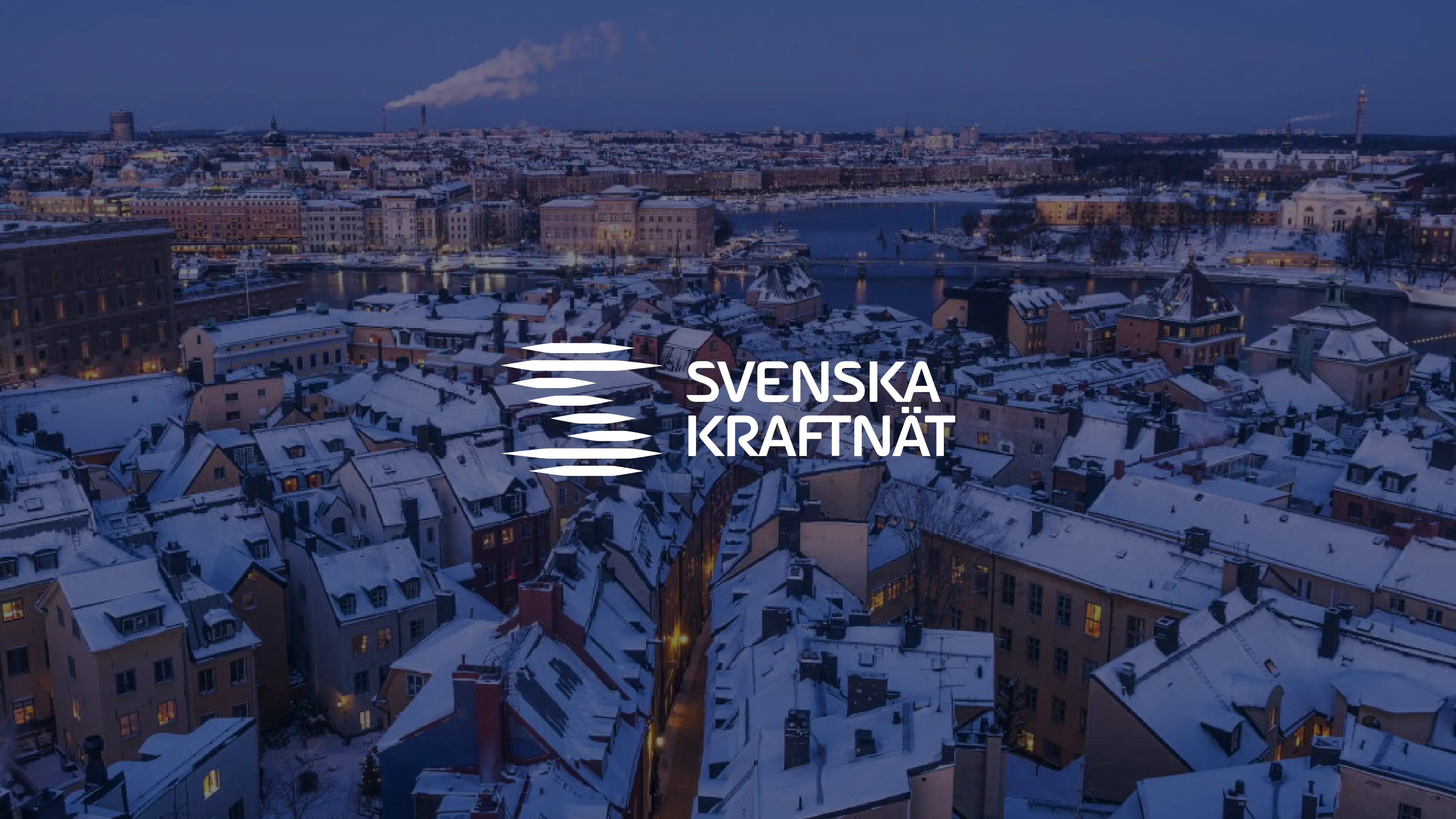 Vogelperspektive auf verschneite Stadt bei Dämmerung mit beleuchtetem Svenska Kraftnät-Logo.