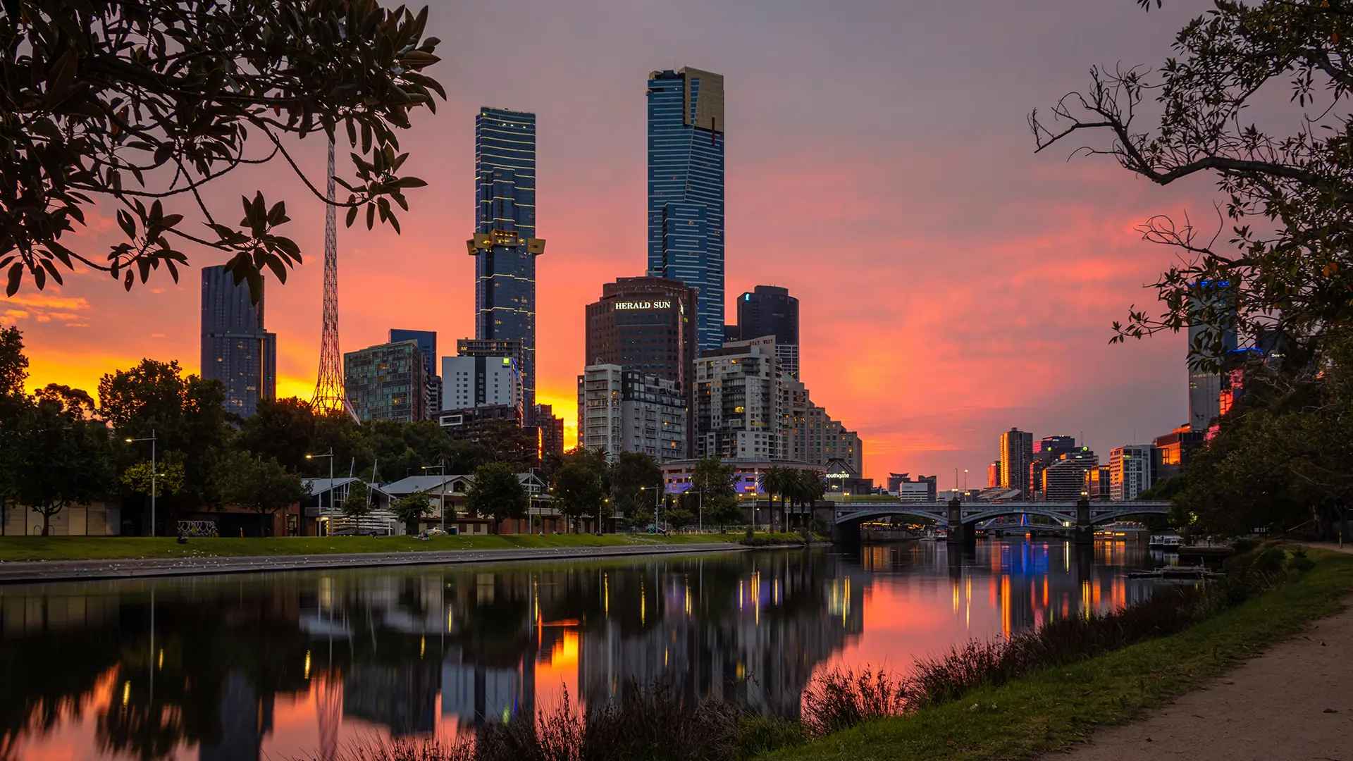 Modern city buildings reflected in a river at sunset