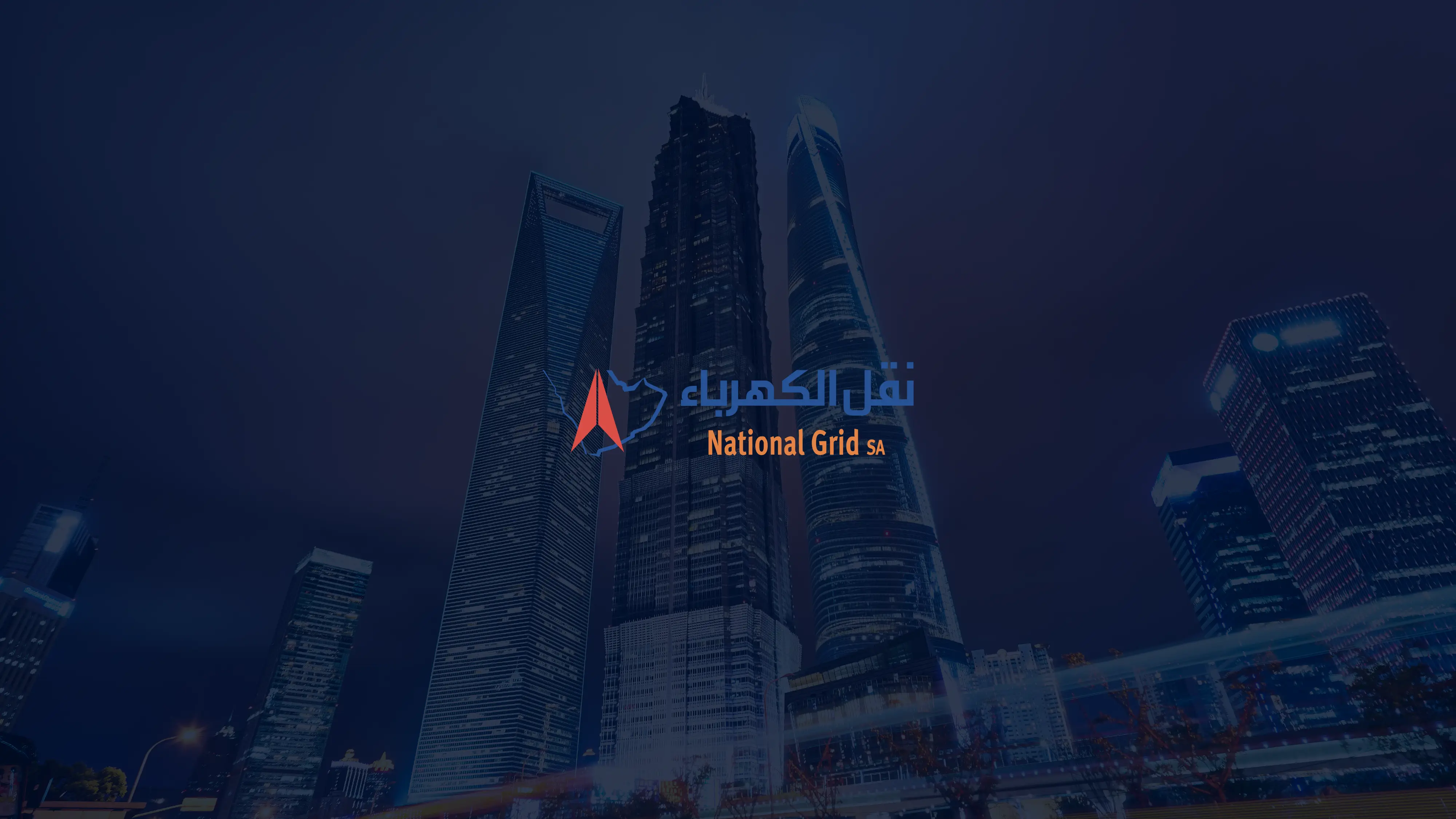 Nighttime city skyline with illuminated skyscrapers and National Grid SA logo in Arabic and English.